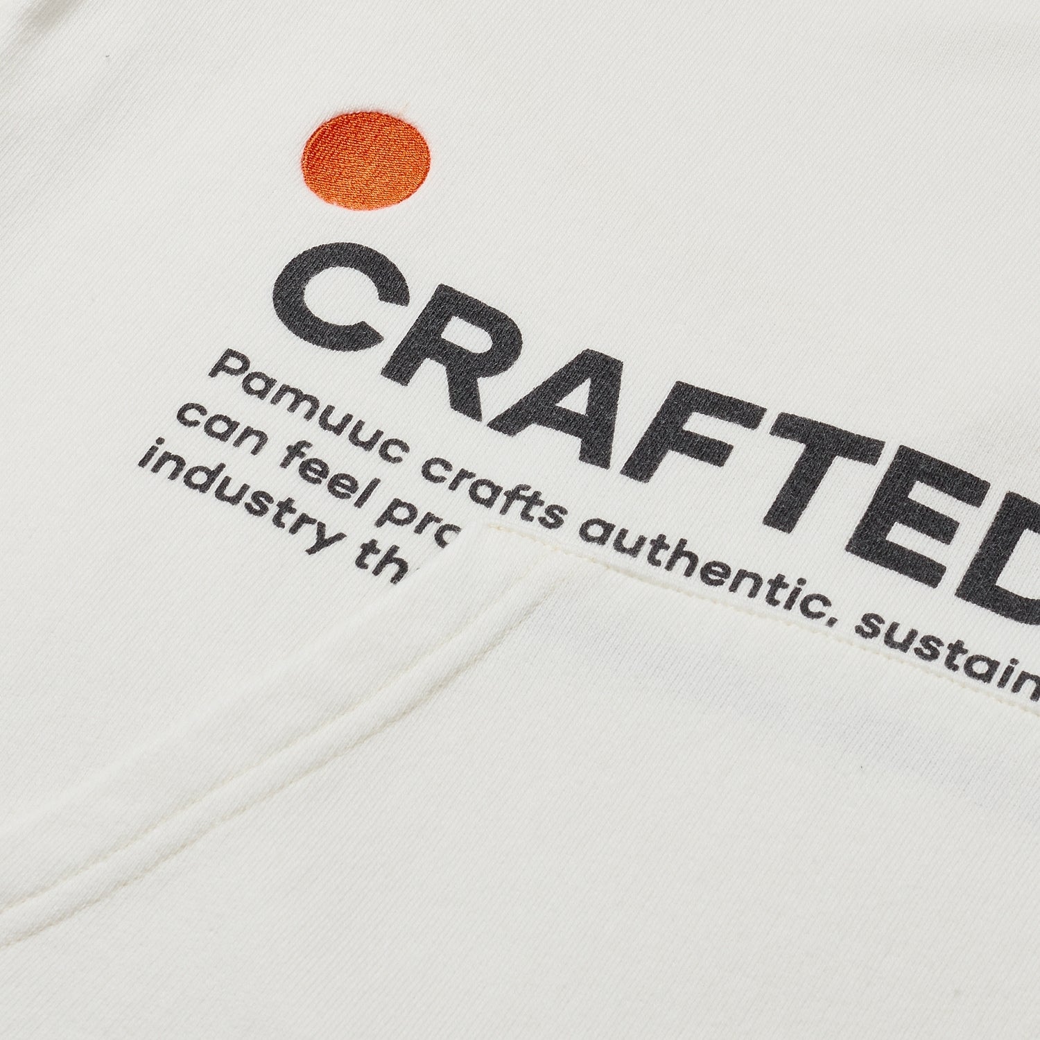 Close-up of white hoodie's fabric with "Crafted to Inspire" slogan and Pamuuc logo.