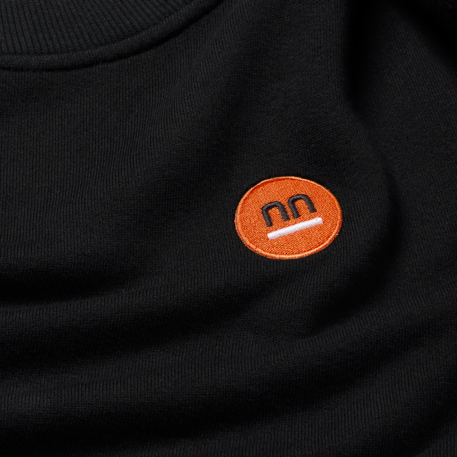 Black fabric made of 100% organic cotton with Pamuuc isotope orange embroidered logo.