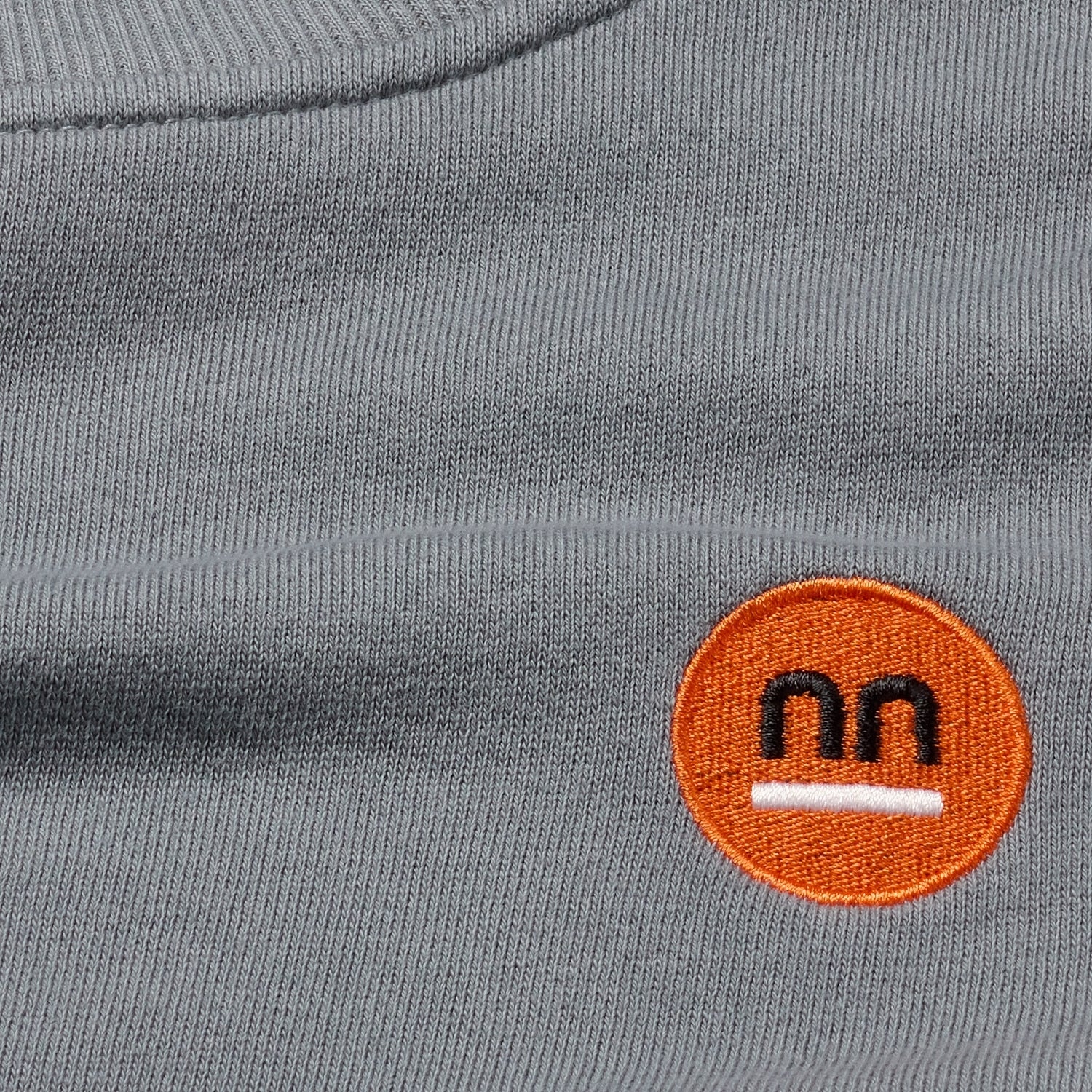 Close-up of grey women crewneck fabric and embroidered logo 